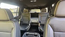 Inside of luxury vehicle with captain chairs and a third row down to show an ample trunk